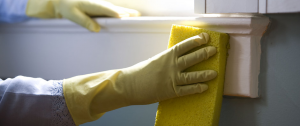 A cleaner cleaning a wall wearing yellow rubber gloves